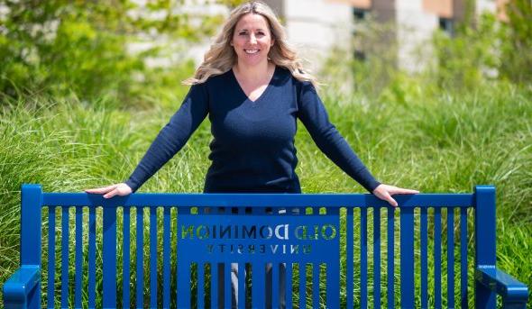 Headshot of woman smiling and standing behind a bench